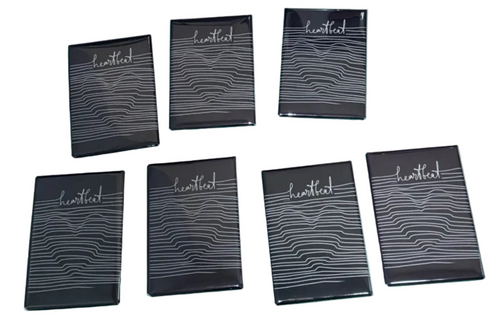 Set of black notebooks with 'heartbeat' text on a black surface with lines and a heart in the background